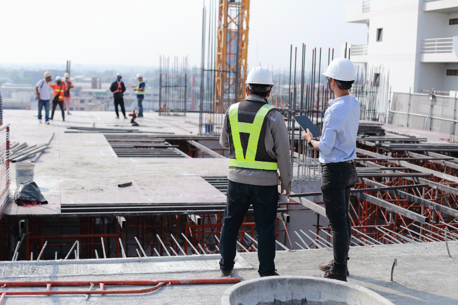 Construction workers working on a site with an insurance inspector