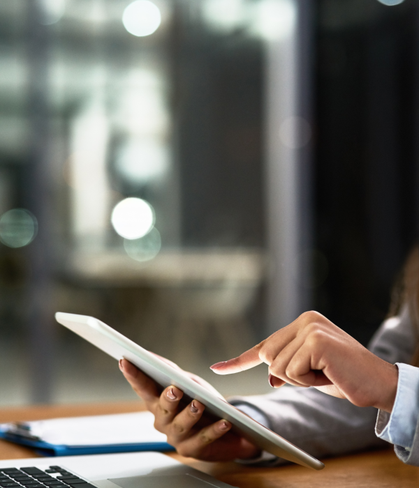 An image of a woman working at her desk on her ipad